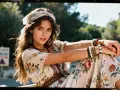 Jeune femme au style hippie Woodstock, robe fleurie, foulard, bracelets en perles, regard intense.