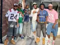 Six hommes posent ensemble, portant des tenues inspirées des années 2000.