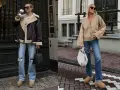 Deux femmes portent des tenues décontractées avec des jeans et des chaussures confortables. L'une a une veste aviateur marron et l'autre un cardigan beige. La tenue avec ugg noir est une option stylée pour l'automne.
