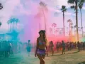 Ambiance festive au thème Coachella, avec une foule sous des palmiers et des nuages de fumée colorée rose et bleue.