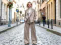 Une femme porte un tailleur pantalon large beige, un col roulé blanc et des sandales. Parfaites quelles chaussures avec un pantalon 7/8 !
