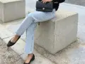 Un look chic pour savoir avec quoi porter des ballerines : jean clair, veste noire et sac matelassé.