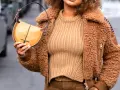 Une femme porte un pull beige côtelé, une veste en fausse fourrure marron et un sac à main jaune moutarde. Le jaune moutarde est une couleur qui va bien avec le beige.