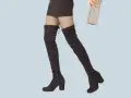 Jambes portant des cuissardes noires et un mini-short, prêtes pour une soirée chic avec une pochette scintillante.