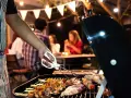 Un homme en tablier rayé prépare un barbecue. Idéal pour savoir comment s'habiller pour un barbecue : décontracté et pratique !