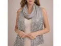 Une femme porte une étole grise à paillettes sur une robe de soirée. Idéal pour savoir comment porter une étole sur une robe de soirée.