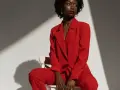 Une femme porte un tailleur pantalon rouge vif, un exemple parfait de comment porter un blazer rouge femme avec assurance.