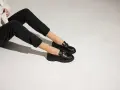 Une tenue décontractée avec un jean noir et une veste claire, rehaussée par une élégante tenue avec mocassin femme orné d'une chaîne dorée.