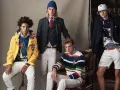 Quatre jeunes hommes posent dans un style preppy, arborant des vestes colorées, des pulls rayés et des pantalons blancs.