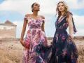 Deux femmes portent des robes fleuries, une rose et une bleu nuit, évoquant la couleur demoiselle d'honneur parfaite pour un mariage champêtre.