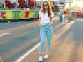 Une jeune femme porte un jean mom et des baskets blanches, un look parfait pour une journée à la fête foraine.