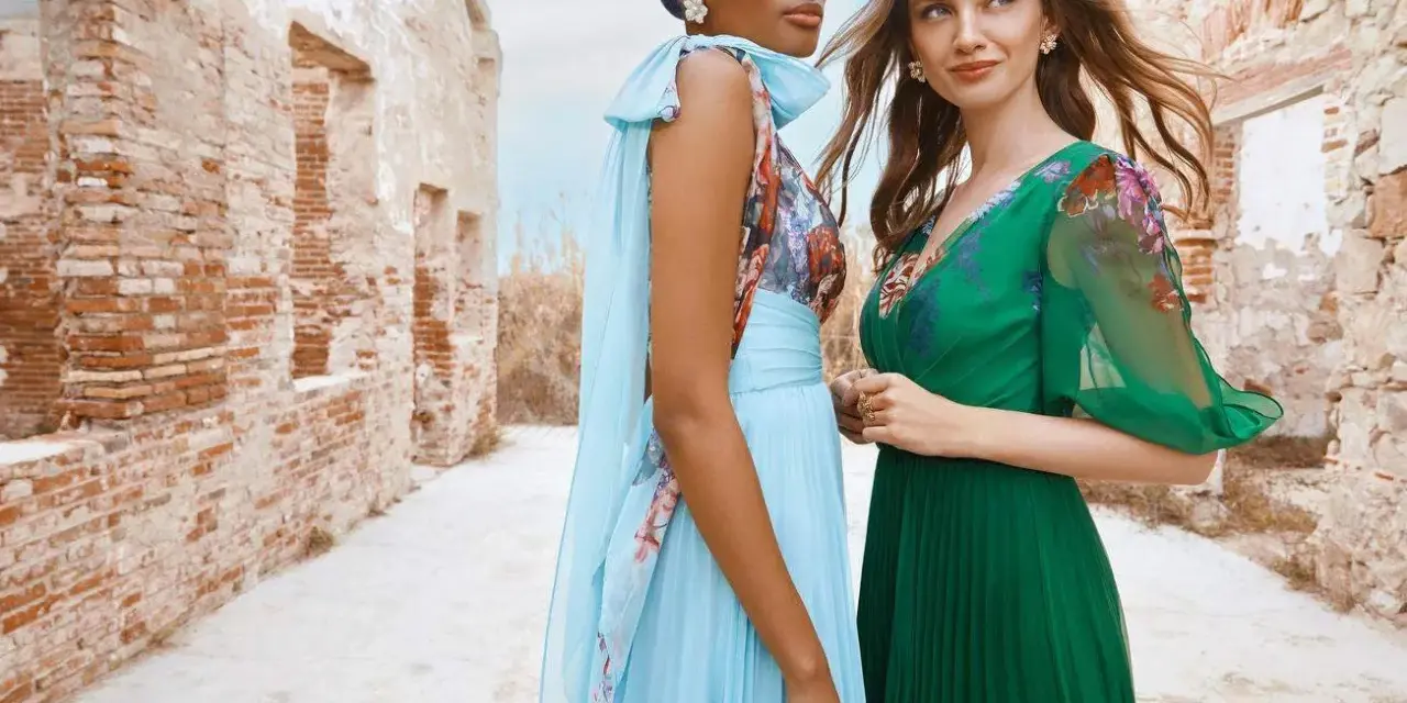 Deux femmes portent des robes élégantes, parfaites pour une tenue mariage avril. L'une est en bleu ciel plissé, l'autre en vert émeraude.