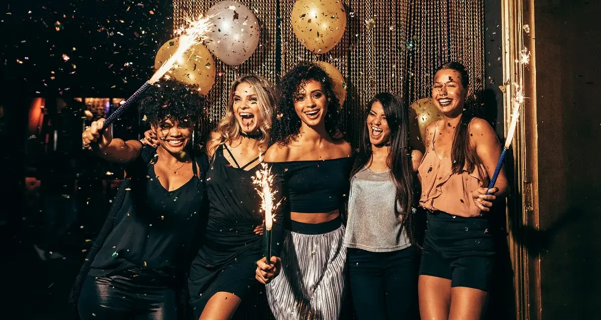 Cinq amies célèbrent avec des étincelles et des confettis. Une parfaite idée tenue boite de nuit pour une soirée mémorable.