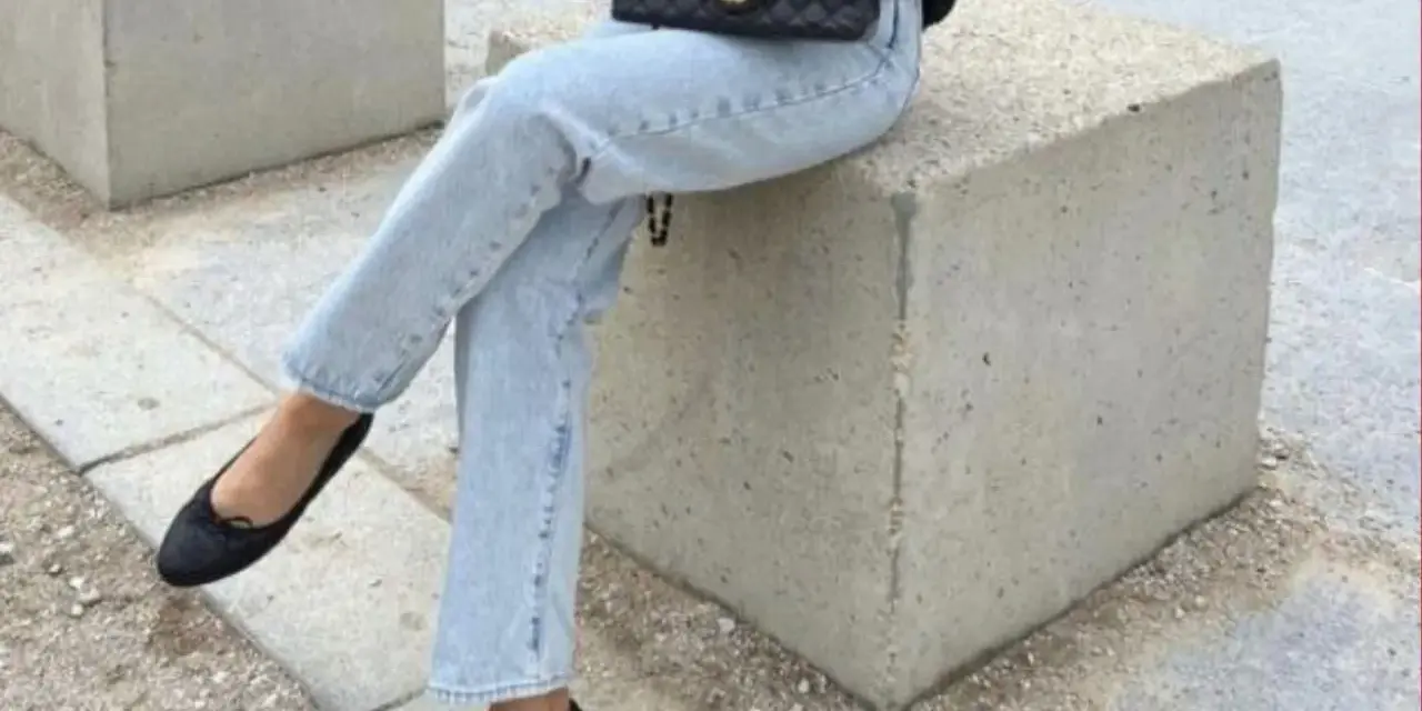 Un look chic pour savoir avec quoi porter des ballerines : jean clair, veste noire et sac matelassé.