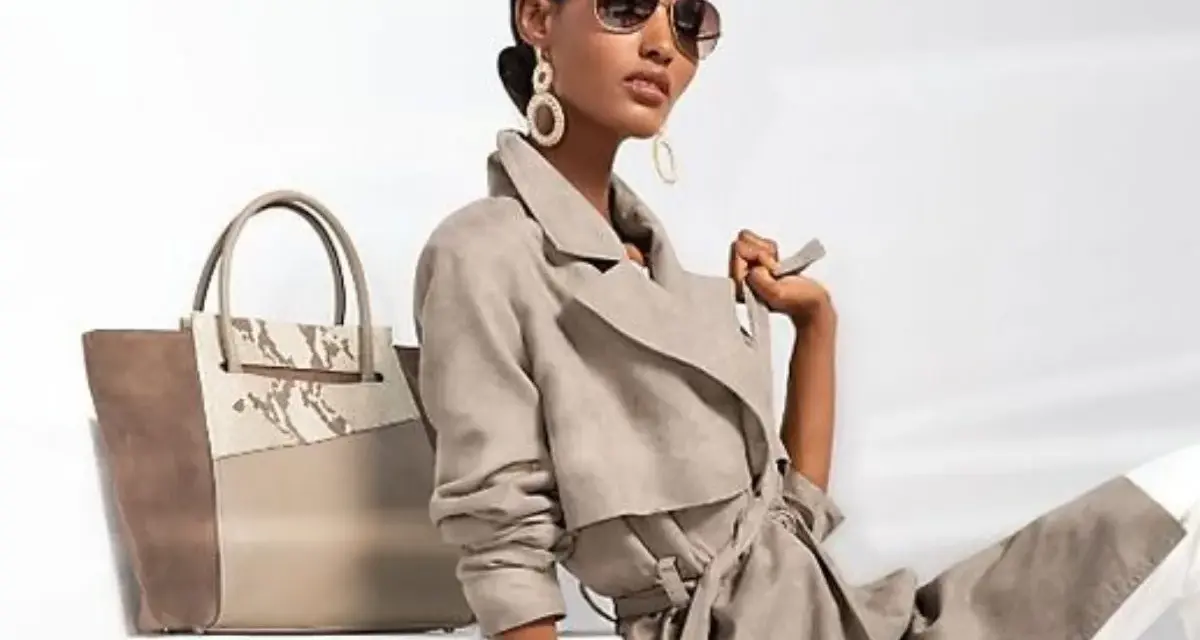 Une femme incarne le **style classique femme** avec un trench léger, des lunettes aviateur et un grand sac bicolore.