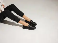 Une tenue décontractée avec un jean noir et une veste claire, rehaussée par une élégante tenue avec mocassin femme orné d'une chaîne dorée.