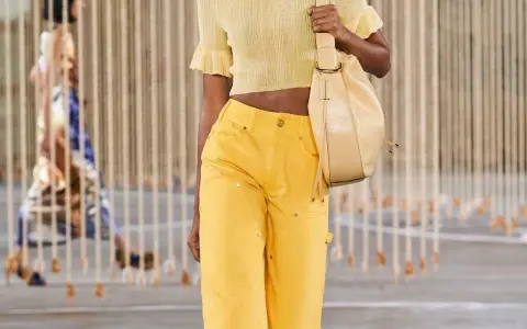 Mannequin portant une tenue de soirée en jean jaune vif, un haut court assorti et un sac beige.