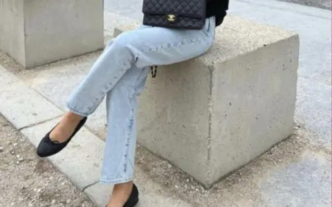 Un look chic pour savoir avec quoi porter des ballerines : jean clair, veste noire et sac matelassé.