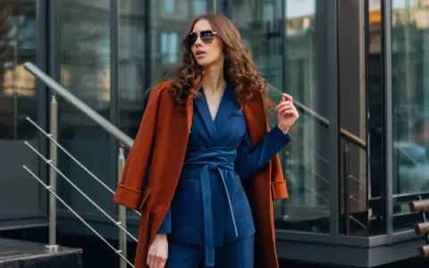 Quelle veste avec robe bleu marine pour mariage ? Un manteau rouille chic complète cette tenue élégante.