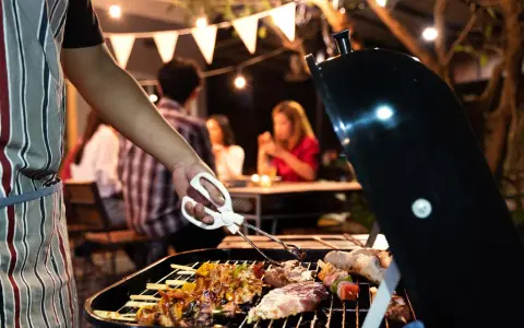 Un homme en tablier rayé prépare un barbecue. Idéal pour savoir comment s'habiller pour un barbecue : décontracté et pratique !