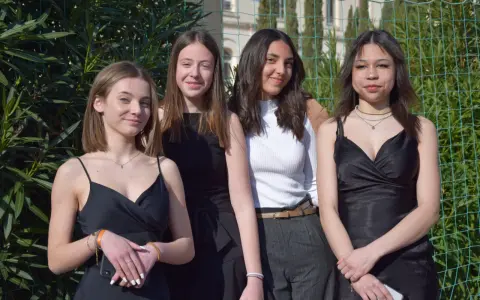 Quatre jeunes femmes posent, habillées élégamment. Idées pour comment s'habiller pour l'Aïd : robes noires, haut blanc chic, et accessoires discrets.