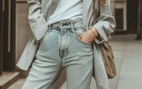 Un blazer gris rayé sur un t-shirt blanc et un **outfit jean bleu** décontracté, avec un sac bandoulière kaki.