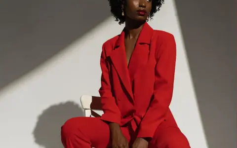Une femme porte un tailleur pantalon rouge vif, un exemple parfait de comment porter un blazer rouge femme avec assurance.