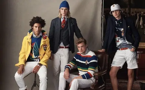 Quatre jeunes hommes posent dans un style preppy, arborant des vestes colorées, des pulls rayés et des pantalons blancs.