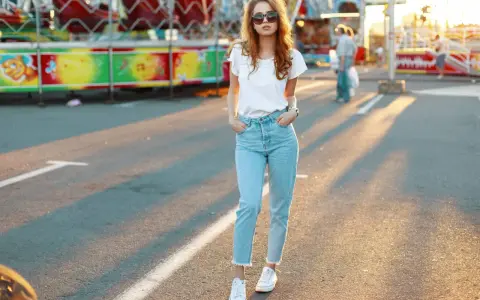Une jeune femme porte un jean mom et des baskets blanches, un look parfait pour une journée à la fête foraine.