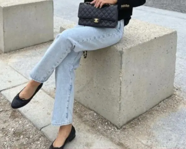 Un look chic pour savoir avec quoi porter des ballerines : jean clair, veste noire et sac matelassé.