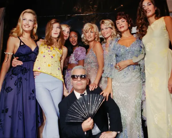 Karl Lagerfeld et des mannequins posent pour une soirée année 90 comment s'habiller. Tenues scintillantes et robes fluides.