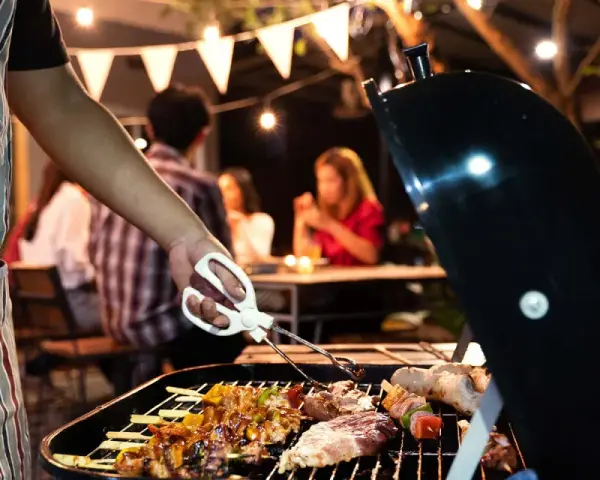 Un homme en tablier rayé prépare un barbecue. Idéal pour savoir comment s'habiller pour un barbecue : décontracté et pratique !