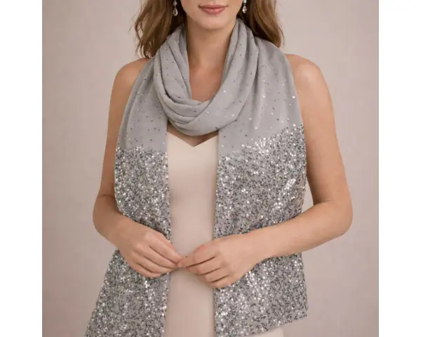 Une femme porte une étole grise à paillettes sur une robe de soirée. Idéal pour savoir comment porter une étole sur une robe de soirée.