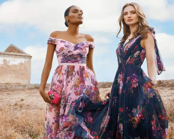 Deux femmes portent des robes fleuries, une rose et une bleu nuit, évoquant la couleur demoiselle d'honneur parfaite pour un mariage champêtre.
