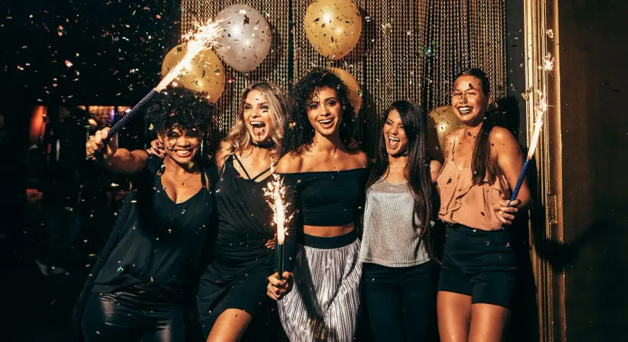 Cinq amies célèbrent avec des étincelles et des confettis. Une parfaite idée tenue boite de nuit pour une soirée mémorable.