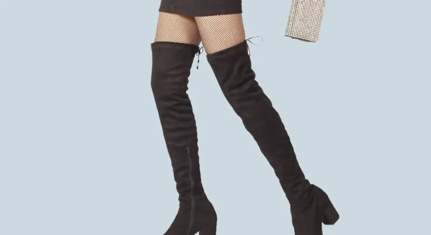 Jambes portant des cuissardes noires et un mini-short, prêtes pour une soirée chic avec une pochette scintillante.