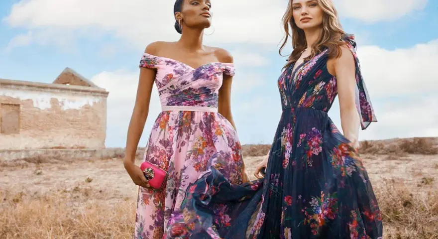 Deux femmes portent des robes fleuries, une rose et une bleu nuit, évoquant la couleur demoiselle d'honneur parfaite pour un mariage champêtre.