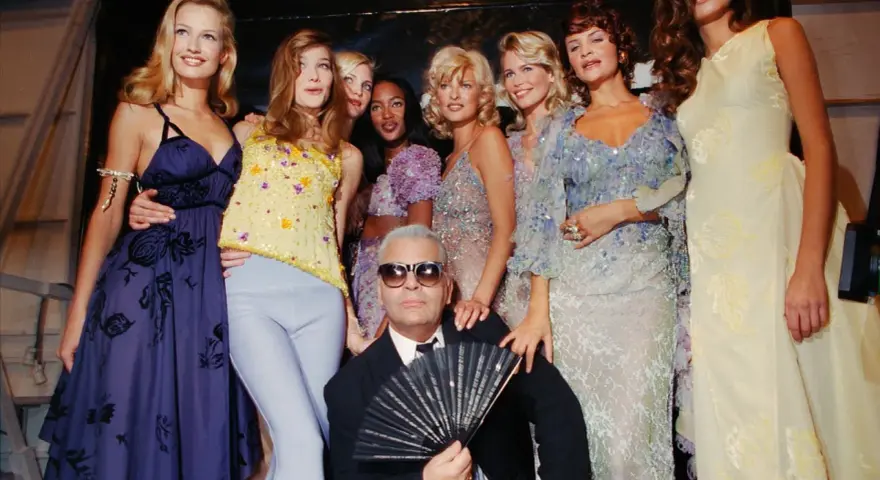 Karl Lagerfeld et des mannequins posent, un éventail à la main, dans un style année 90.