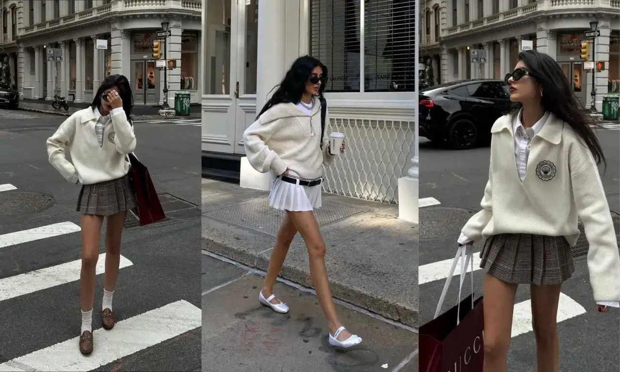 Une jeune femme arbore un look preppy avec un pull blanc, une jupe plissée à carreaux et des mocassins. Elle se promène en ville, un café à la main.