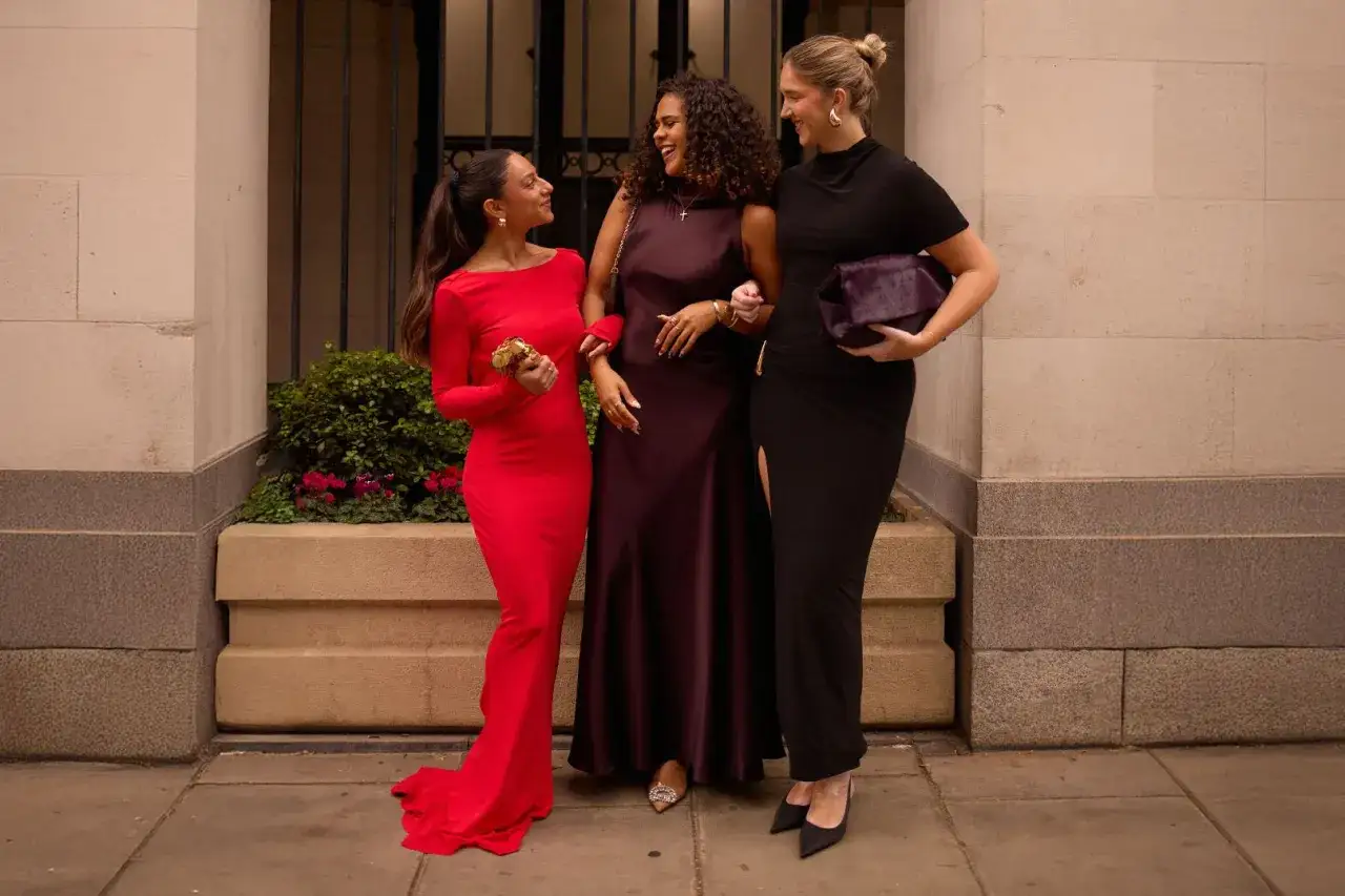 Trois femmes &eacute;l&eacute;gantes discutent, inspirant pour un mariage en hiver comment s'habiller. Robes longues rouges, bordeaux et noires.