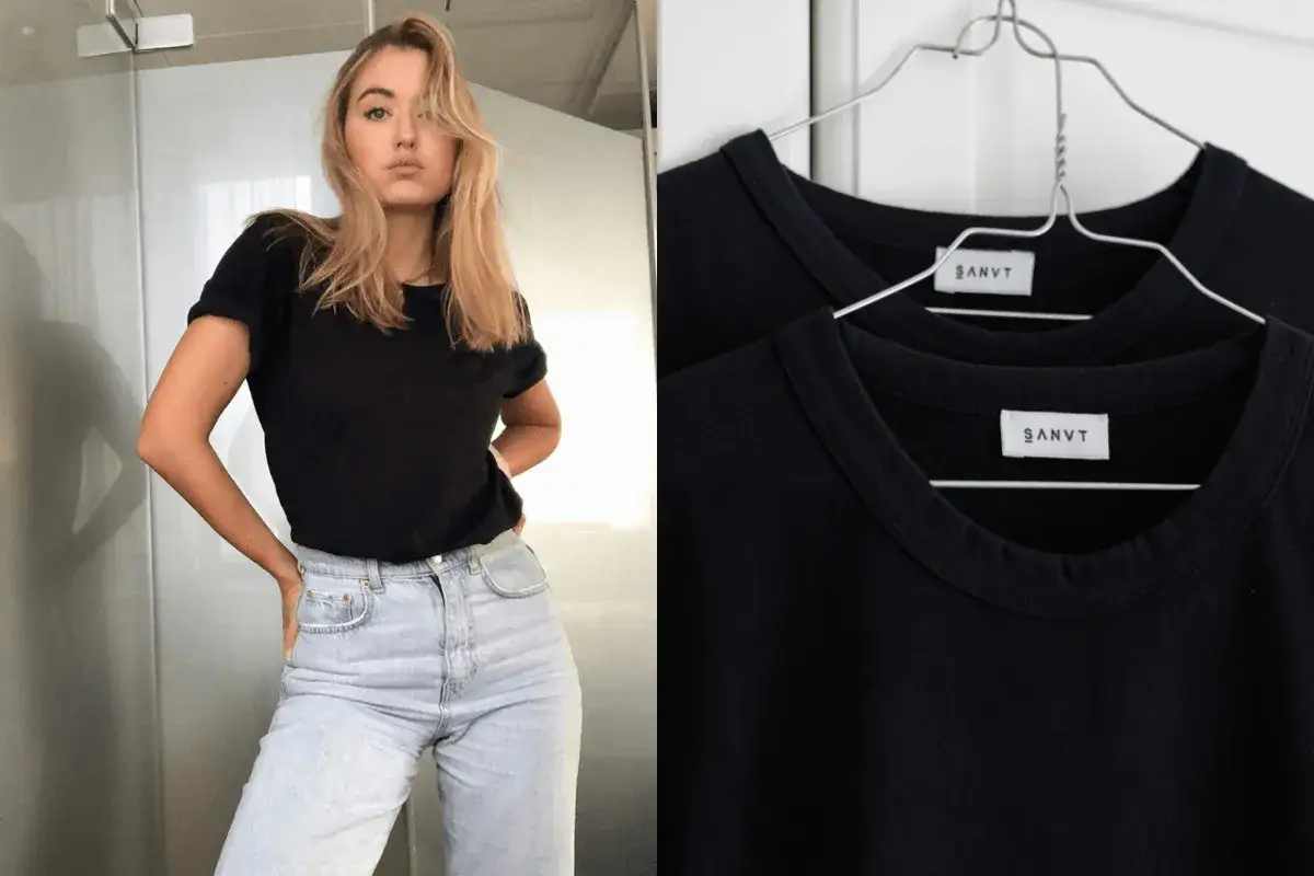 Une jeune femme porte une tenue avec t-shirt noir et jean clair. À côté, deux t-shirts noirs identiques sont suspendus.