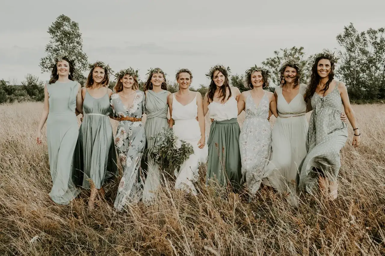 Un groupe de femmes souriantes, couronnées de verdure, dans une prairie dorée. Leur style cottagecore évoque une douce harmonie avec la nature.