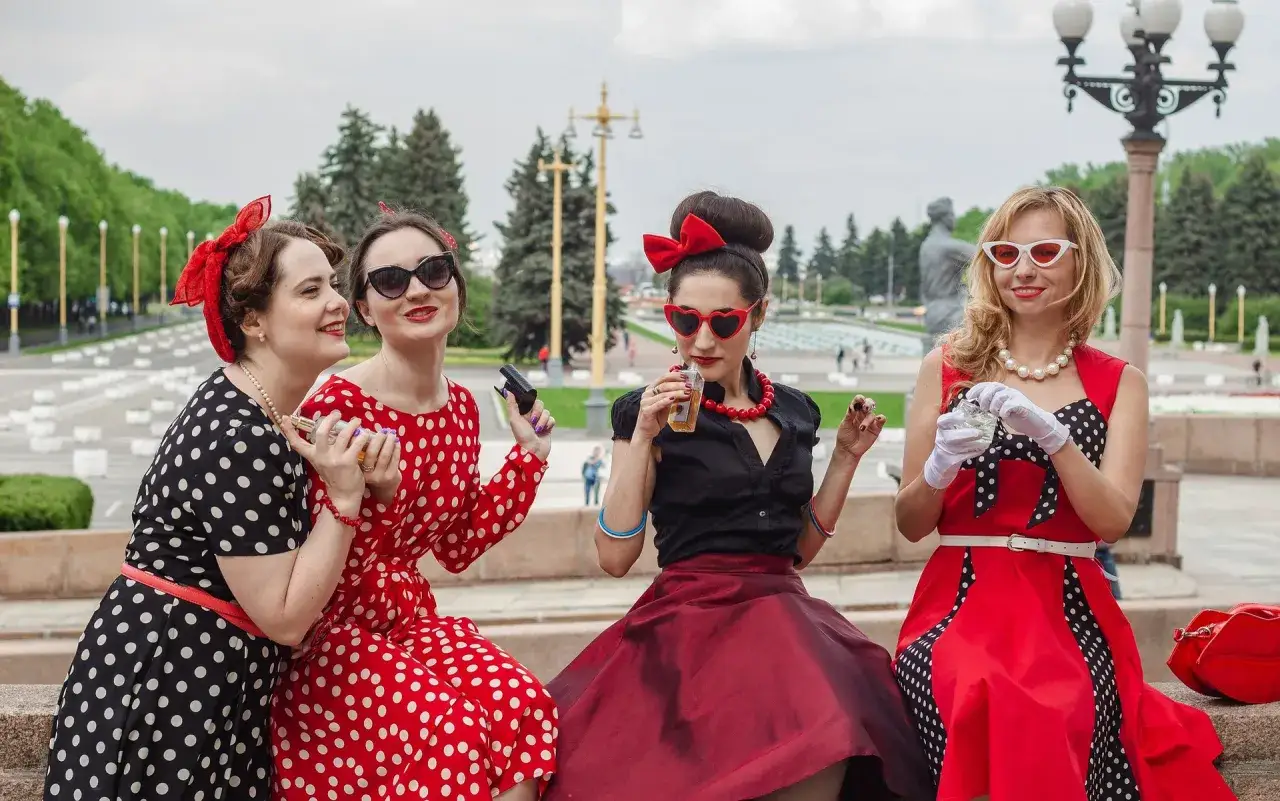 Quatre femmes au style pin-up année 50, robes à pois, lunettes rétro, et accessoires glamour.