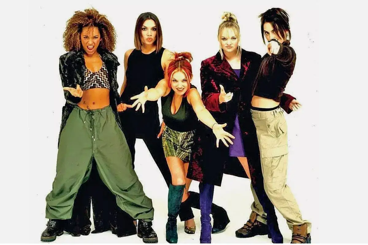 Cinq femmes posent, arborant un style ann&eacute;e 2000 avec des pantalons cargo, des crop tops et des manteaux audacieux.