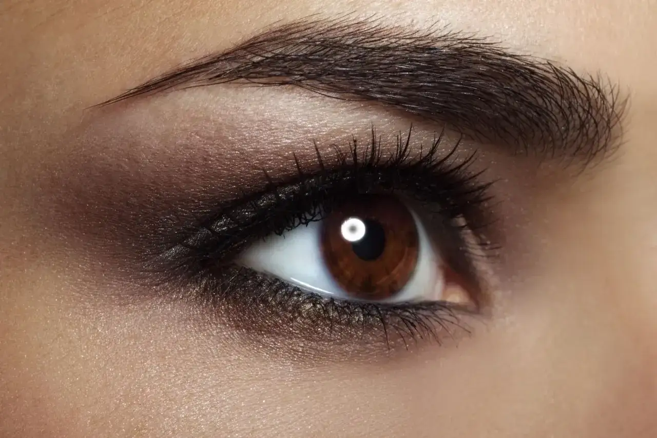 Un œil marron profond, sublimé par une colorimétrie brune et un maquillage sophistiqué.