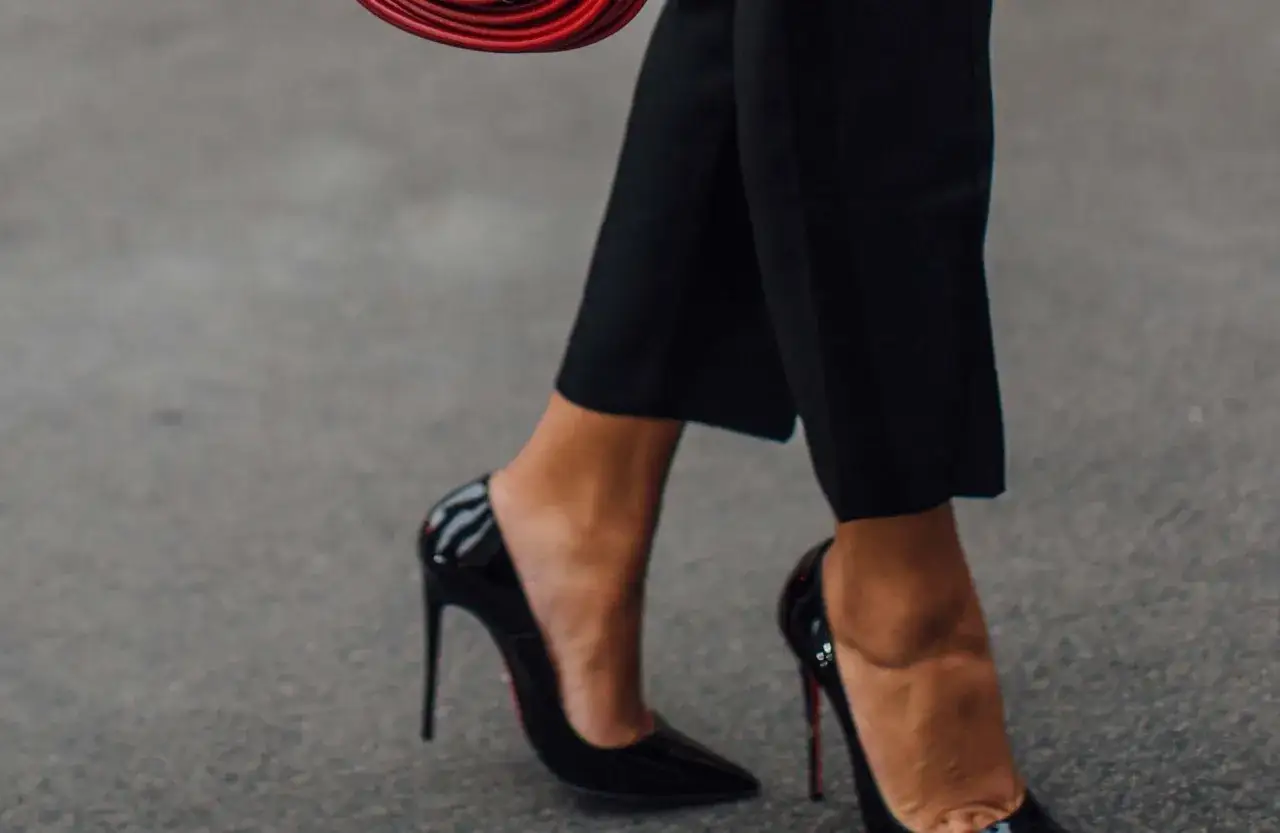Pieds chaussés de talons aiguilles noirs vernis, parfaits avec un pantalon 7/8. Une touche d'élégance pour un look affirmé.