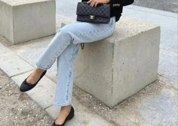 Un look chic pour savoir avec quoi porter des ballerines : jean clair, veste noire et sac matelassé.