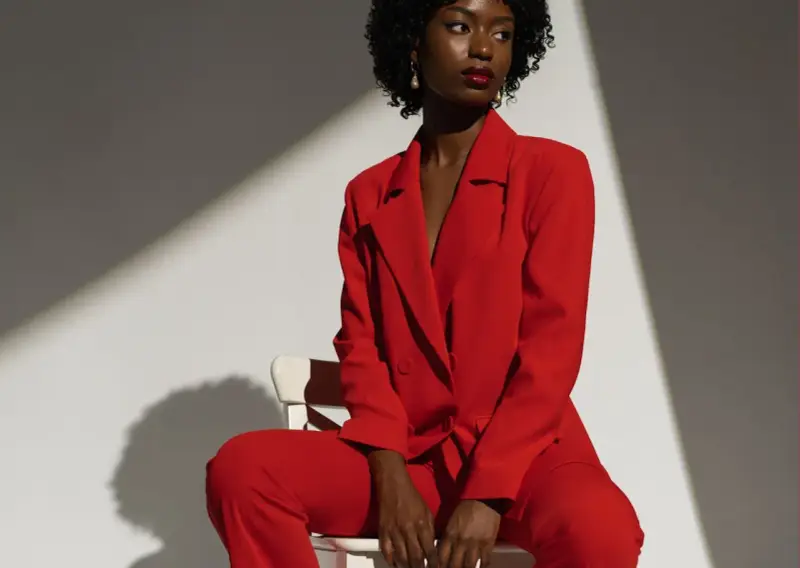 Une femme porte un tailleur pantalon rouge vif, un exemple parfait de comment porter un blazer rouge femme avec assurance.